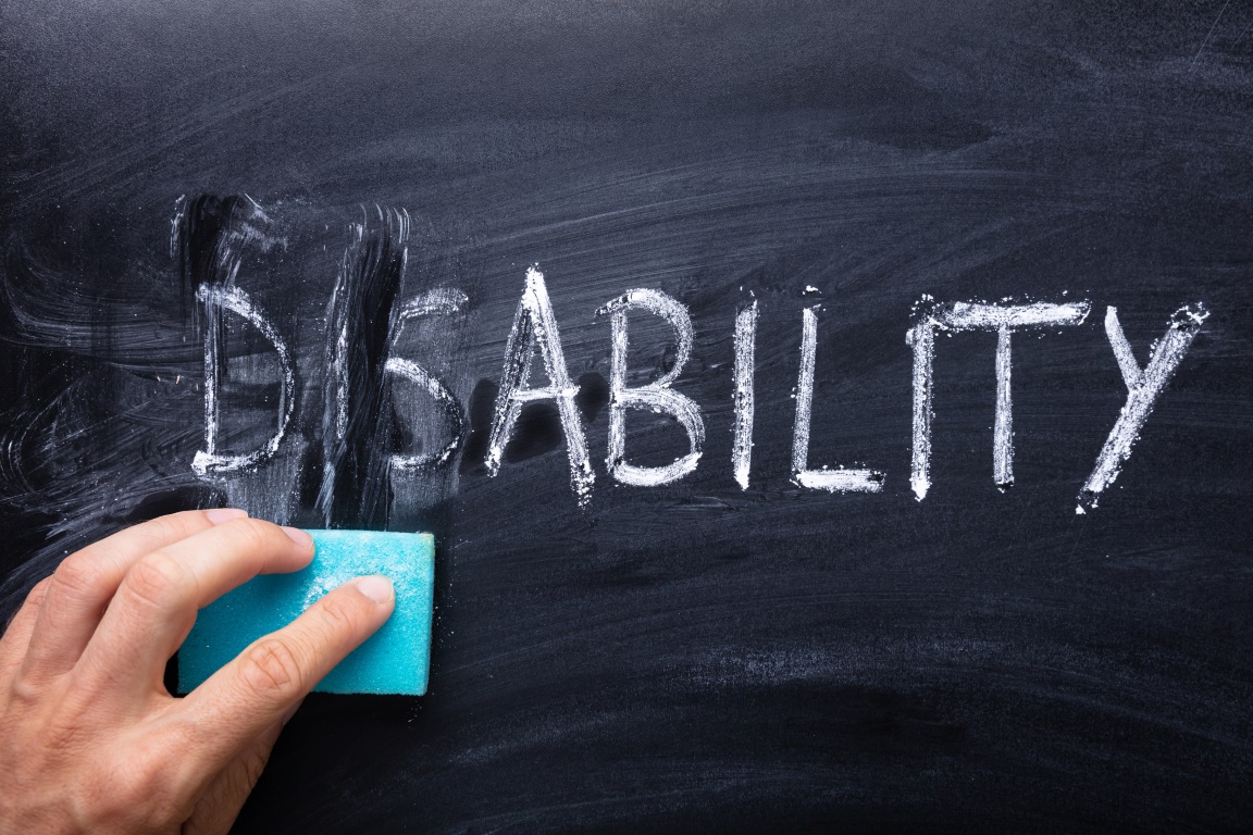 Man's Hand Erasing Dis Text From Disability Word With Sponge Over Chalkboard